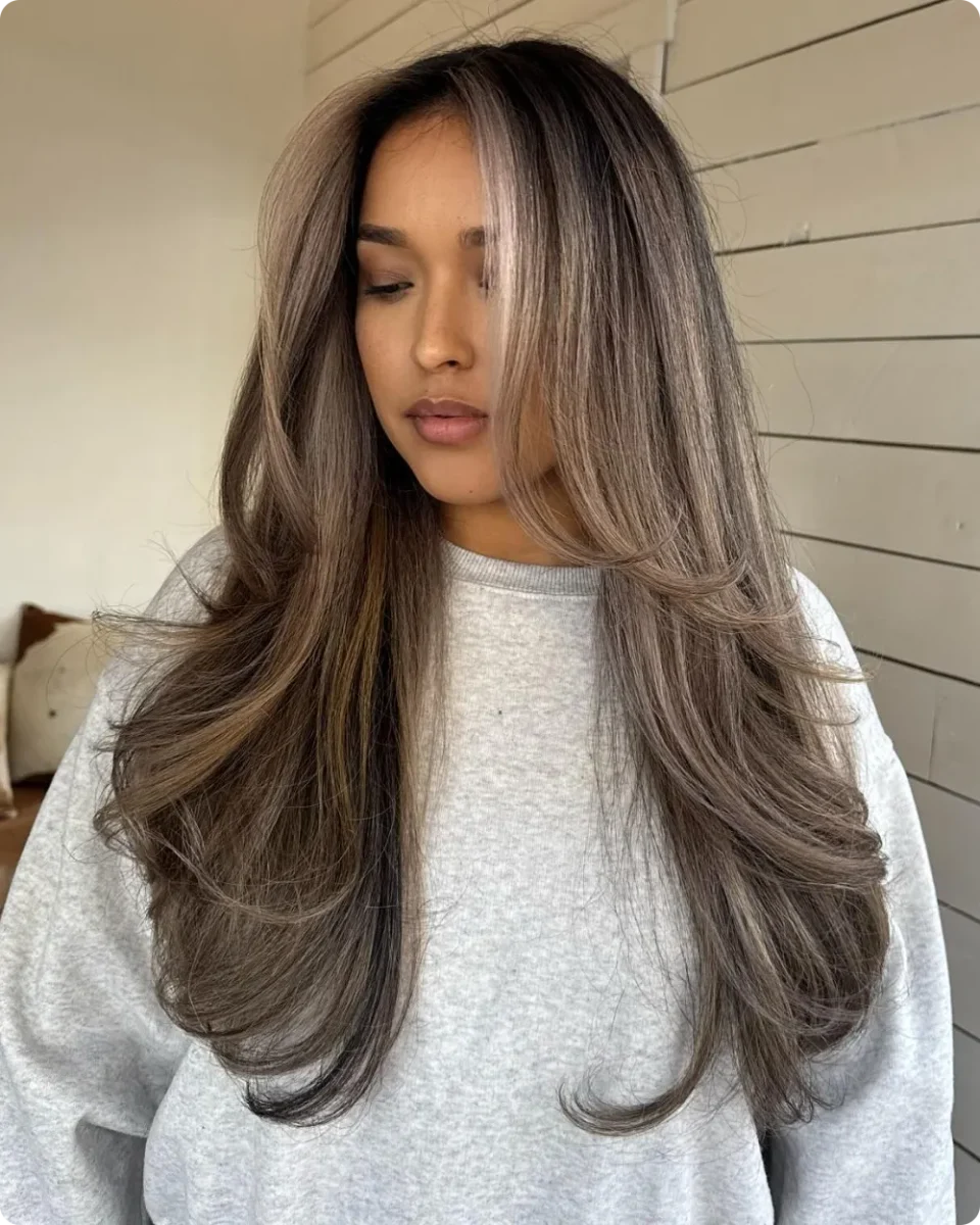 Ash brown long layers with a side part and ends flicking outward below the collarbone