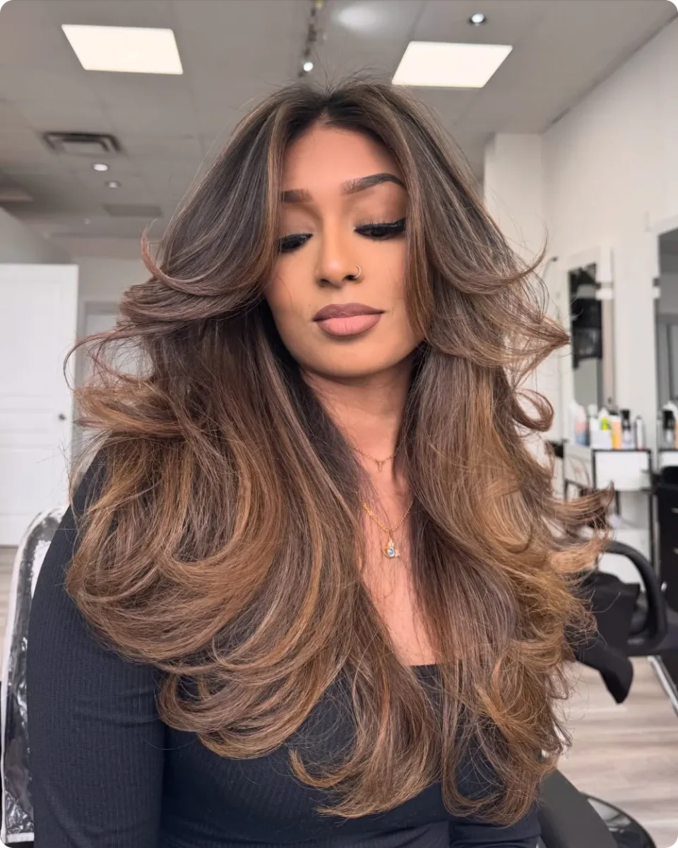 Bouncy caramel layers with root volume and curled ends rolling outward near the waist