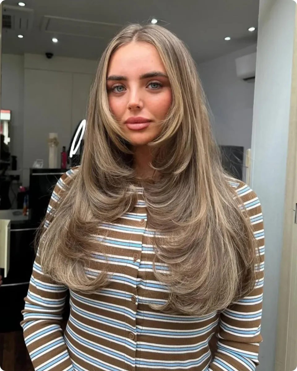 Long layered hair ideas shown on a center part with blonde face framing layers flicked back at the cheekbone