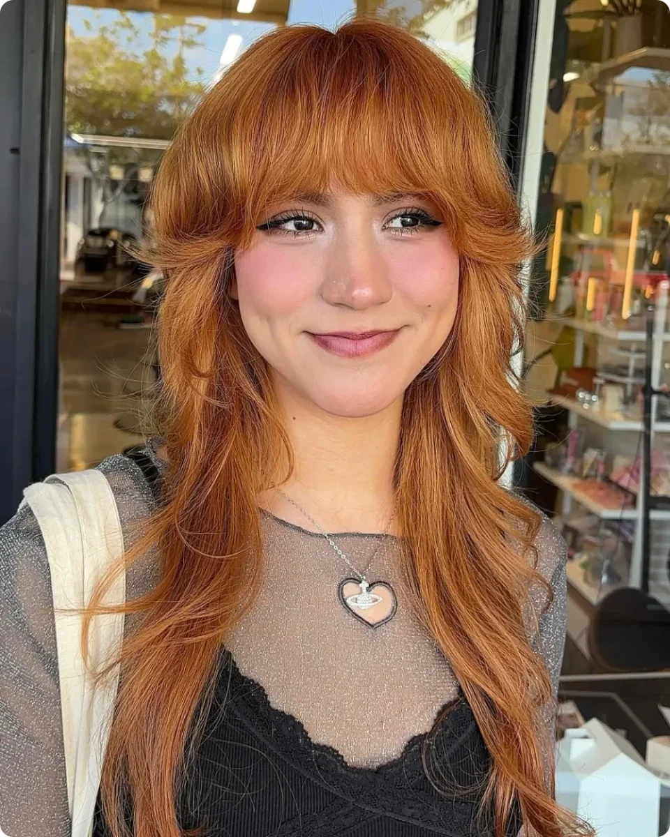 Copper wolf cut with a heavy brow length fringe and shaggy layers at the sides