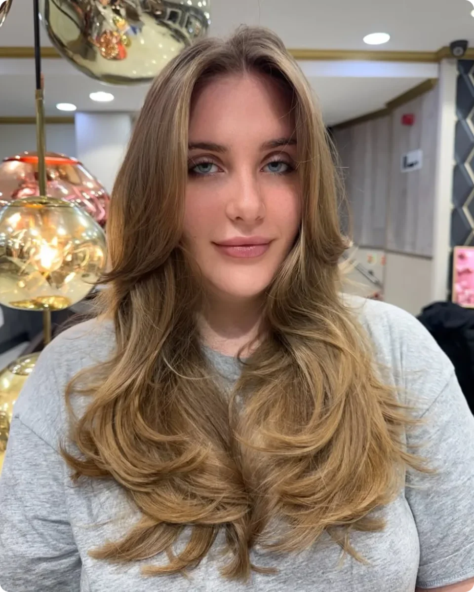 Honey blonde layers with a wide flipped out bottom and golden strands near the face