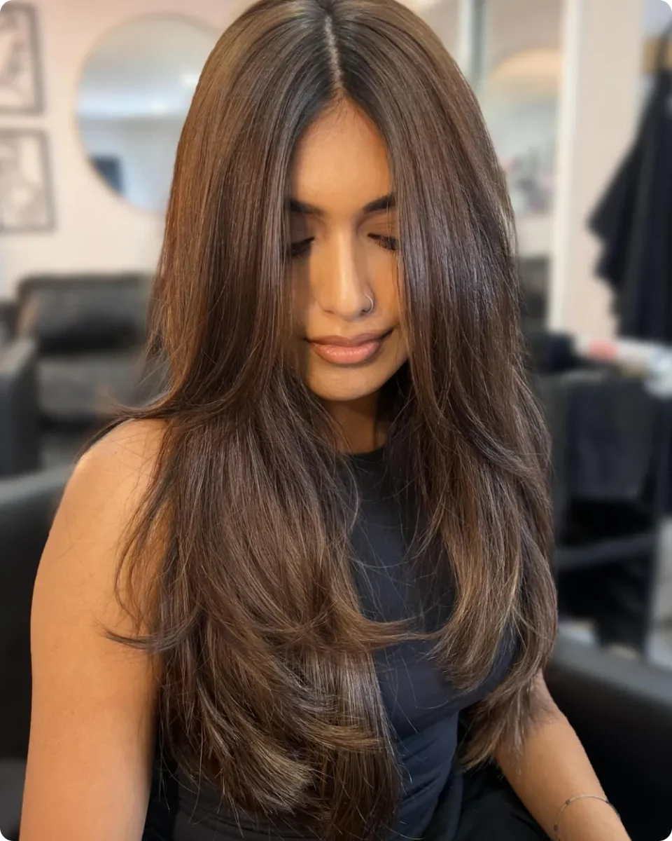 Thick brunette hair cut in long steps from the chin down to the waist