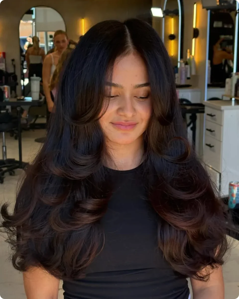 Symmetrical face framing layers curling away from the face on both sides of a center part