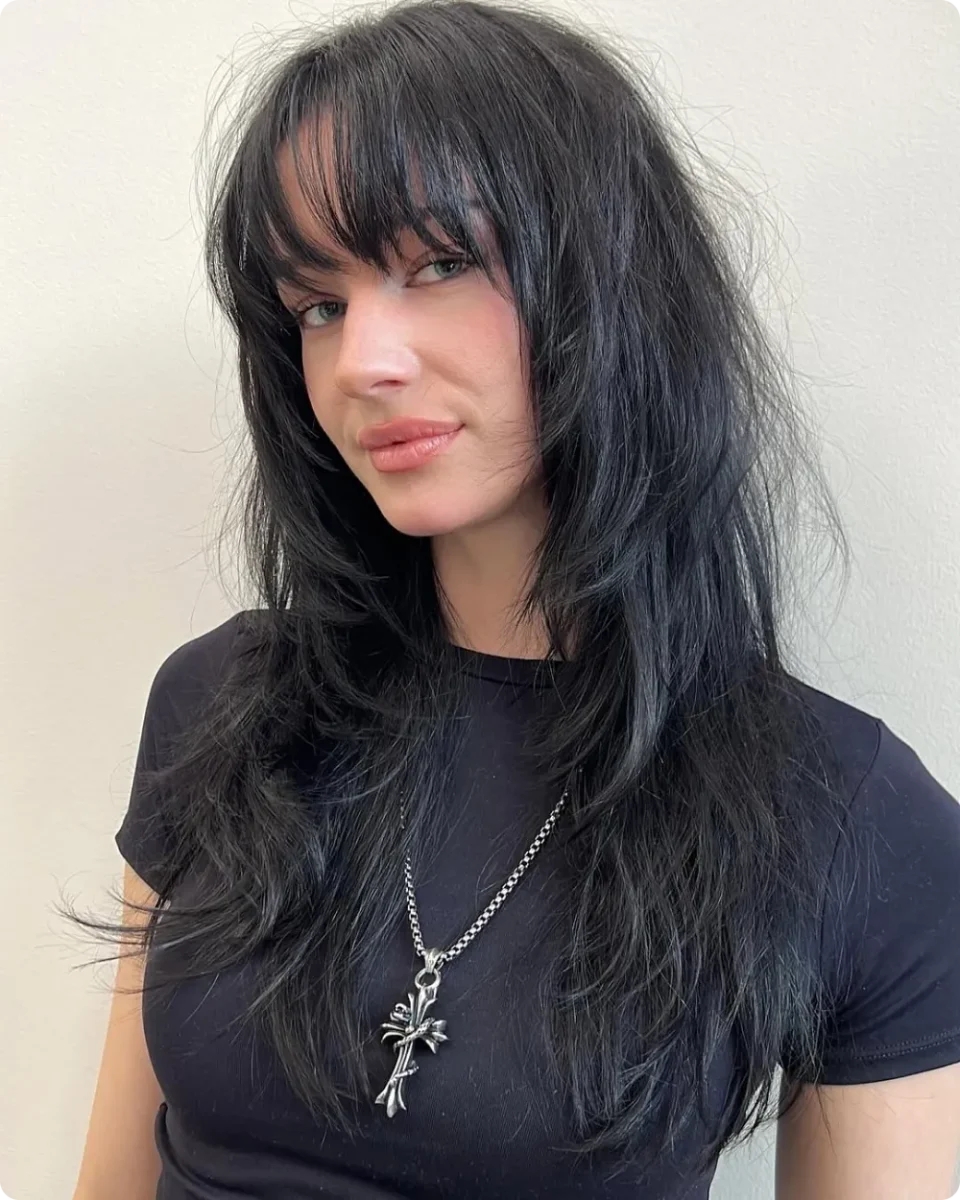 Textured black shag haircut with a full wispy fringe and choppy layers around the face
