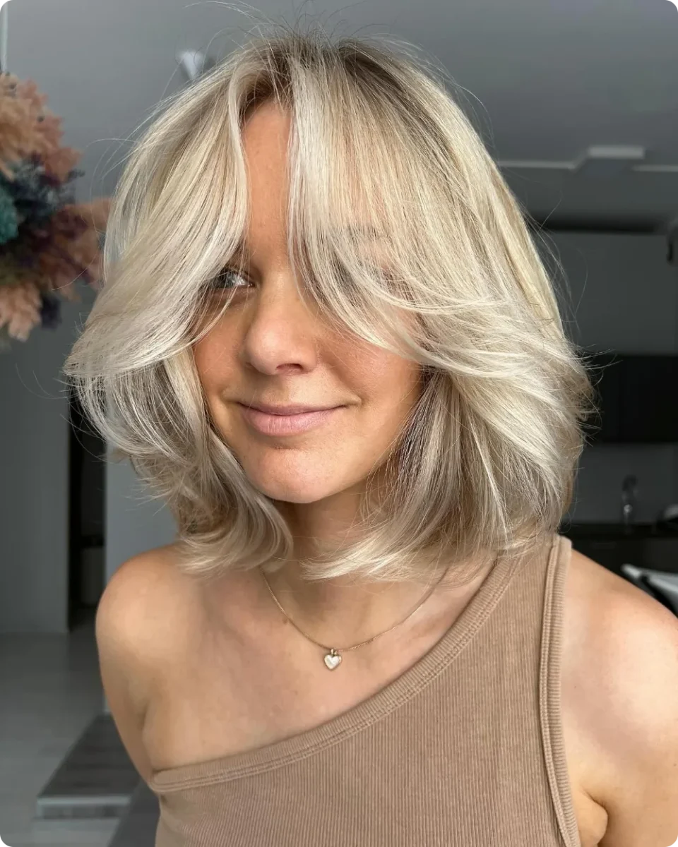 Blonde collarbone bob with curtain bangs and ends flipped outward