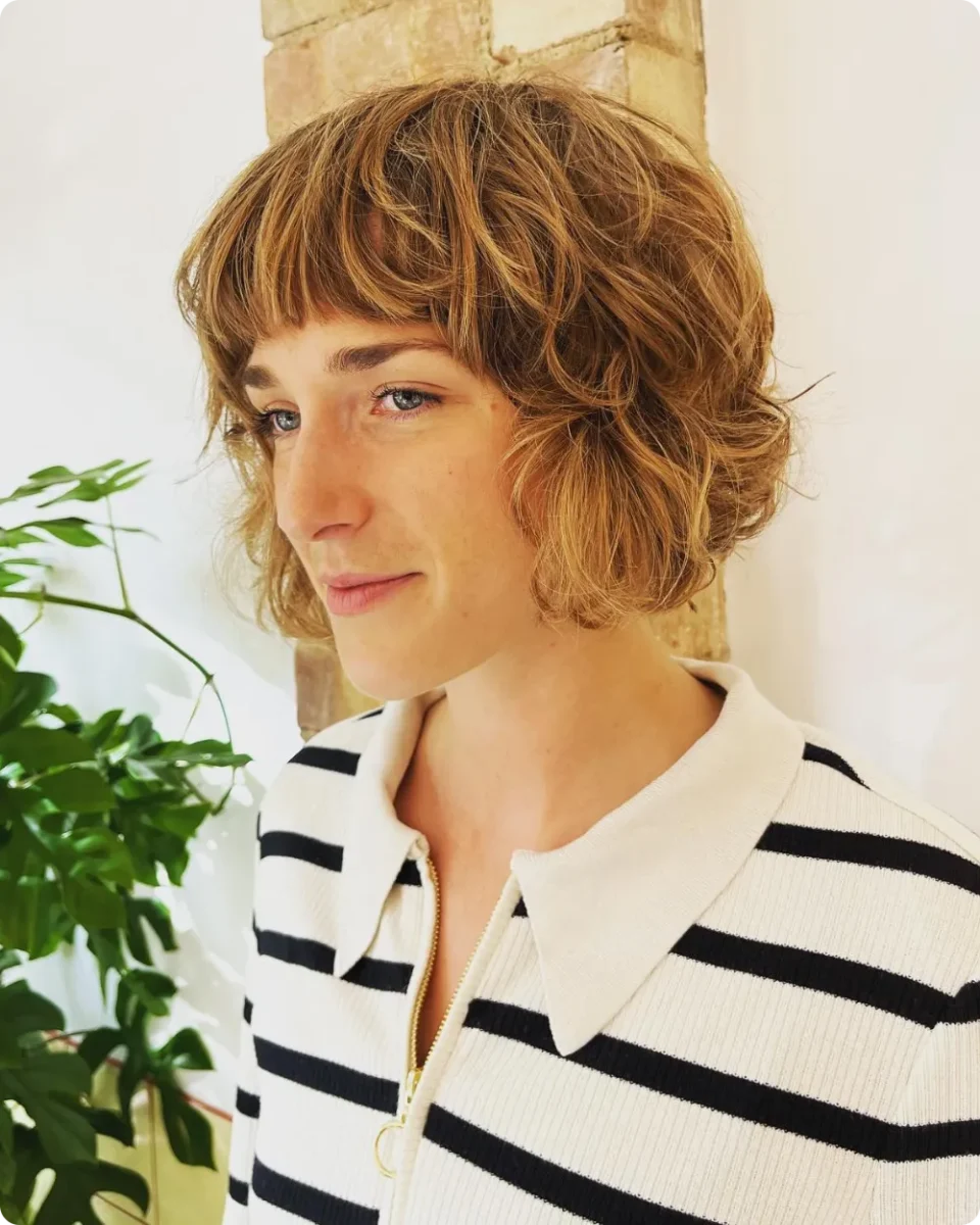 Golden brown curly bob cut to the jaw with a wispy curled fringe