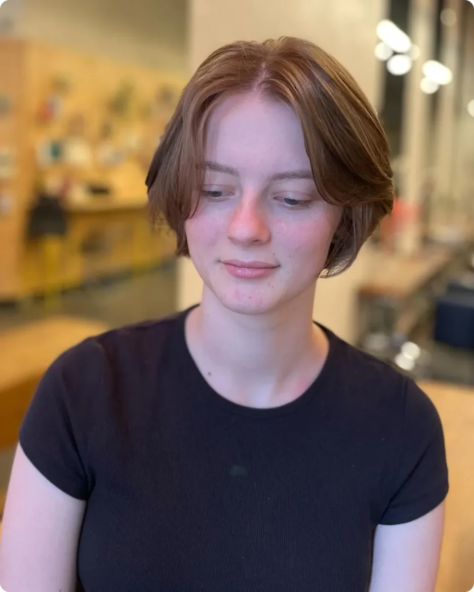 Copper brown ear-length bob tucked behind both ears with a centre part