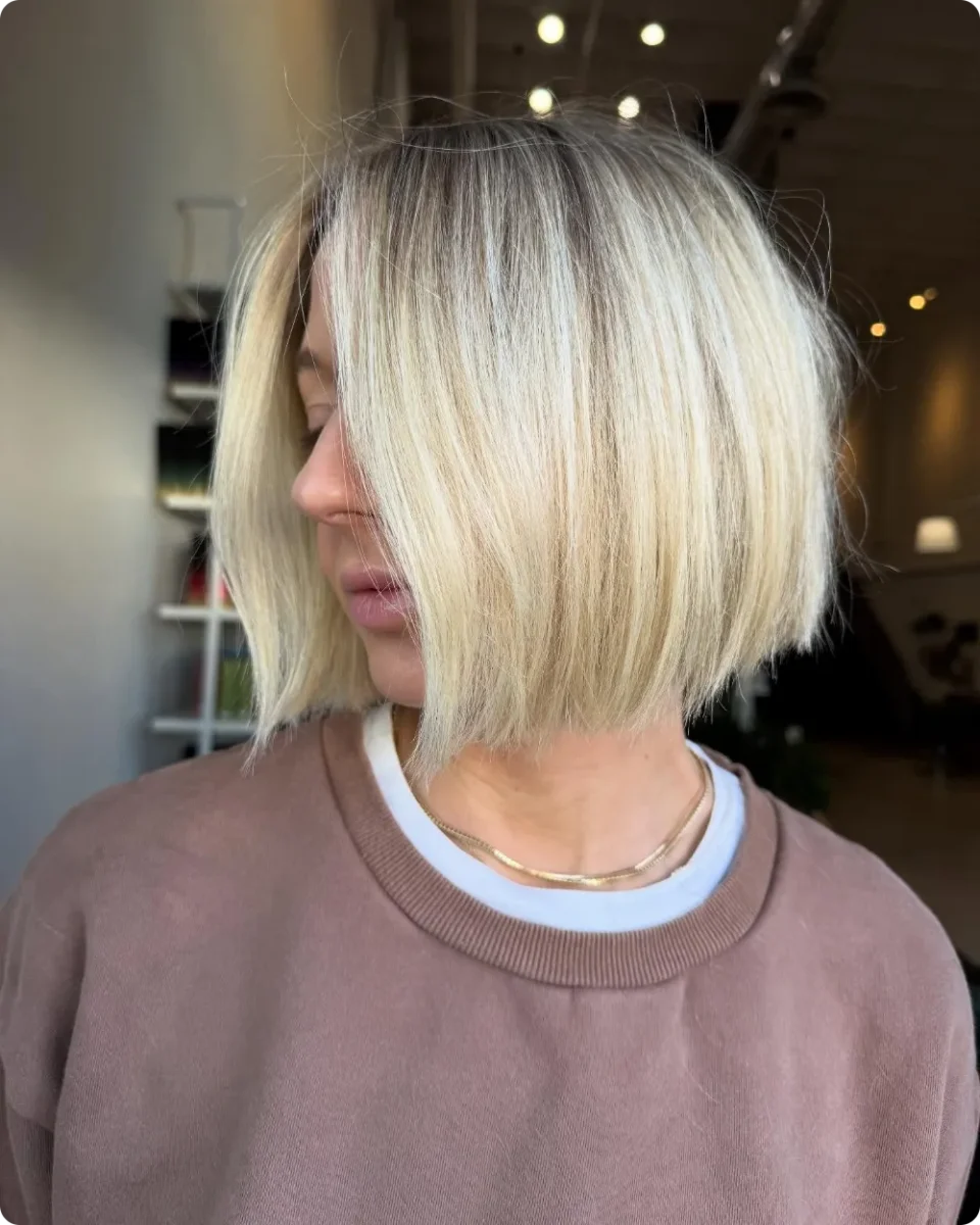 Short blonde A-line bob with a lifted back, shadow root and edged ends